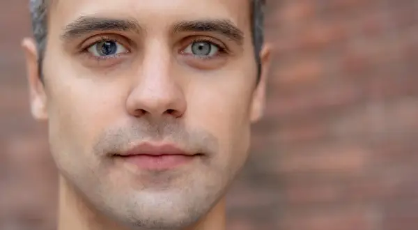 Mężczyzna z heterochromią sektorową. Jedno oko niebieskie z ciemniejszymi fragmentami, drugie szare.