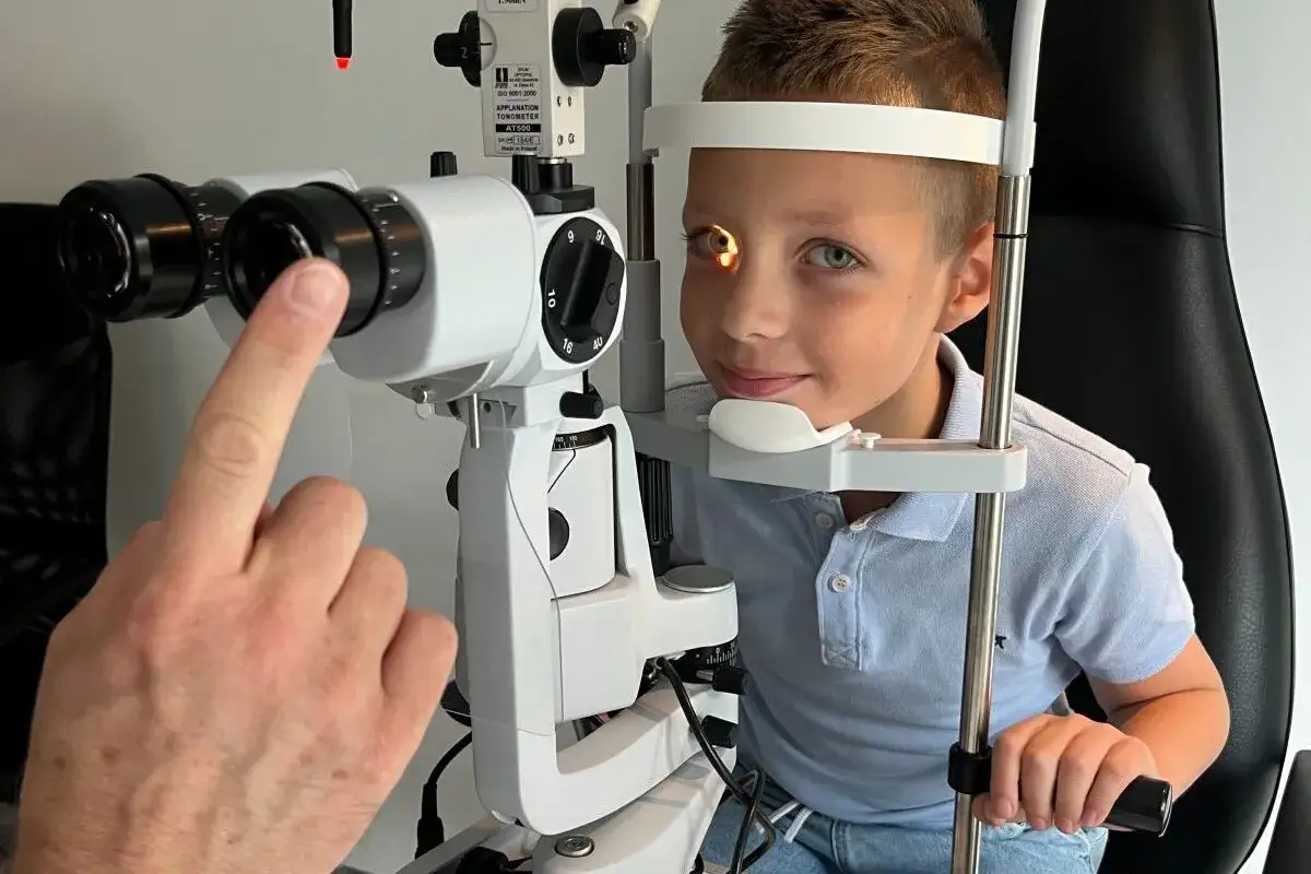 Chłopiec u okulisty, badanie wzroku. Lekarz sprawdza, czy nie ma mroczków przed oczami u dziecka.