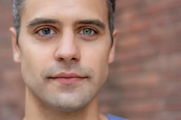 Mężczyzna z heterochromią sektorową. Jedno oko niebieskie z ciemniejszymi fragmentami, drugie szare.